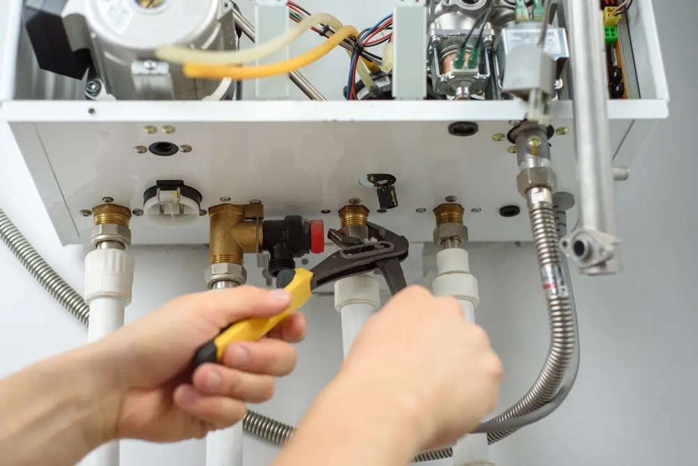 Certified technician using a wrench to tighten gas line fittings on a water heater system to prevent leaks