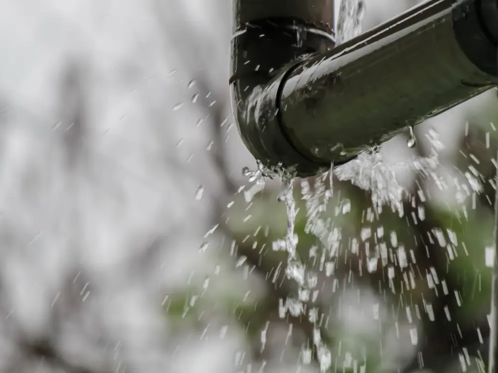 Close-up of a broken pipe elbow spraying water, indicating a severe joint failure and the need for immediate leak detection